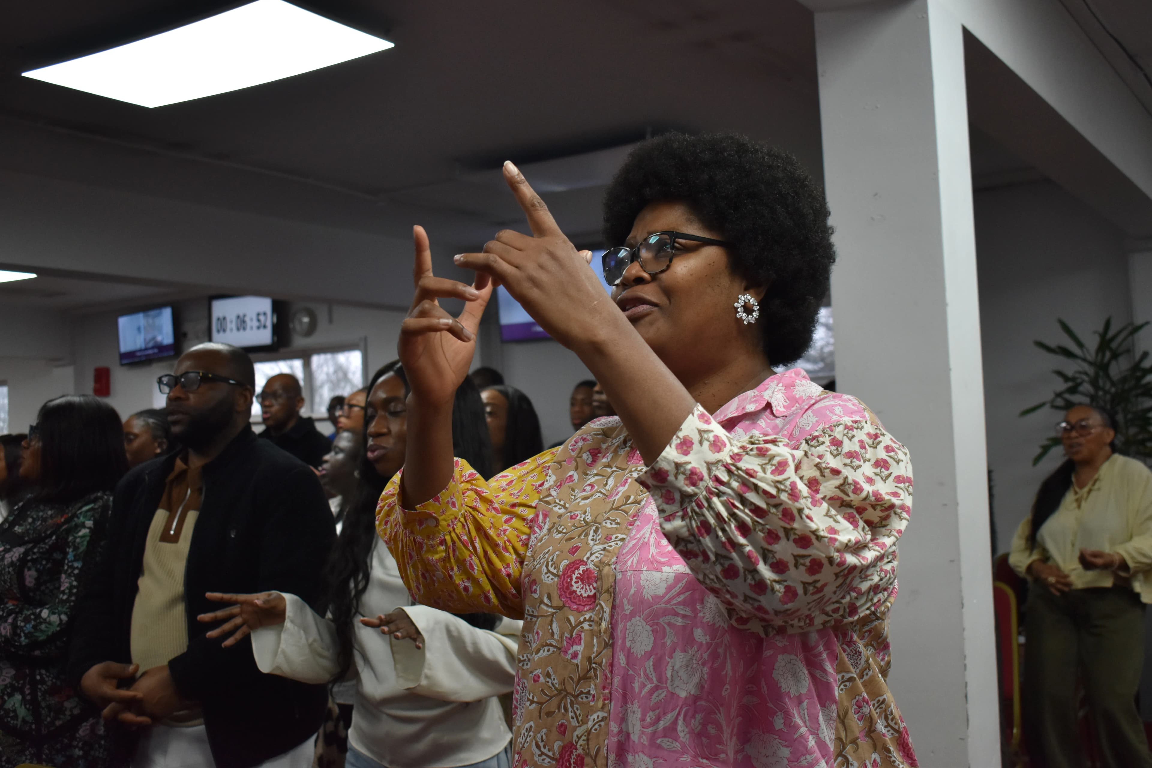 A member of the congregation lifting her hands in prayer.